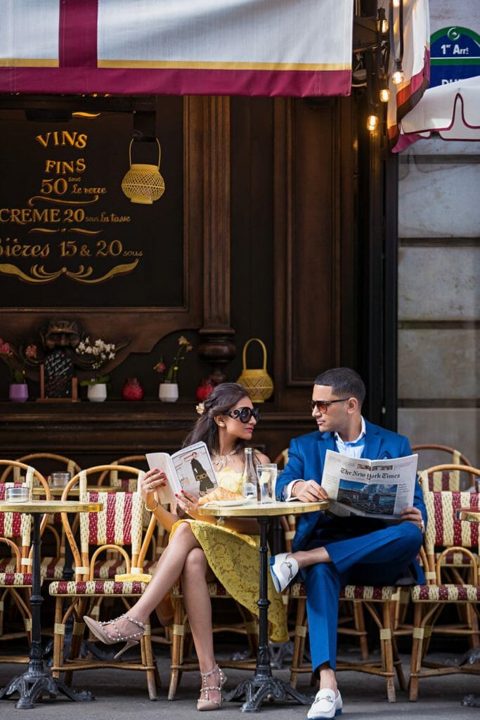 Stylish couple photoshoot Parisian cafe with newspapers