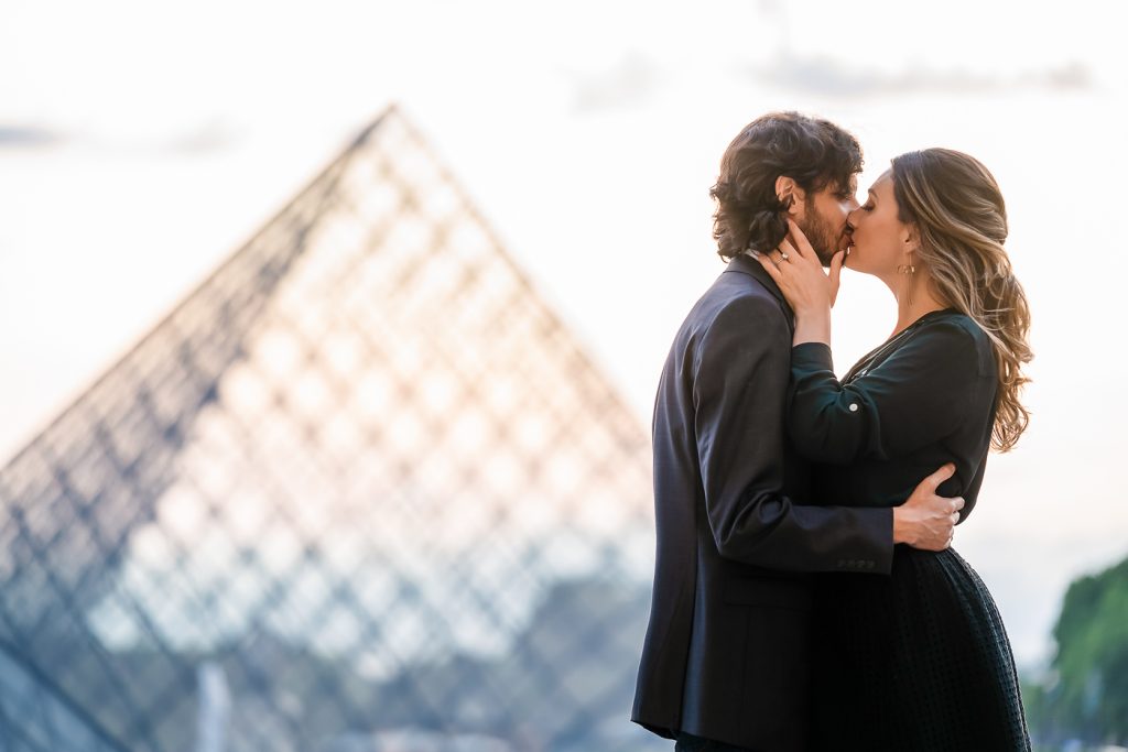 Couple kissing at the Louvre Pyramid at sunset
