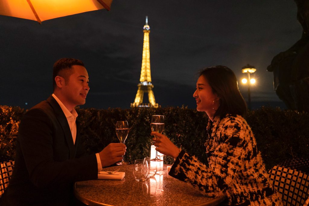 Nighttime Eiffel Tower engagement photos at Cafe de l'Homme with Champagne