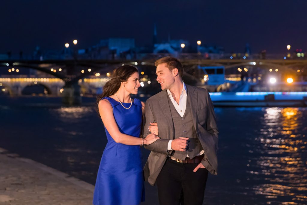 Romantic photo with couple strolling along the Seine at night