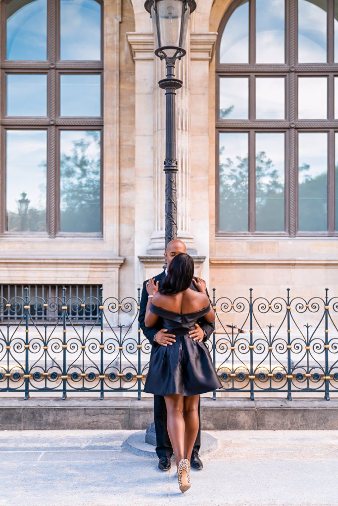 Couple stealing naughty kisses at the Louvre in the evening