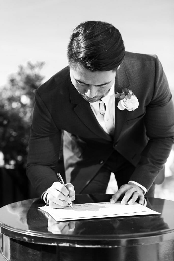 groom signing wedding certificate in black and white photos
