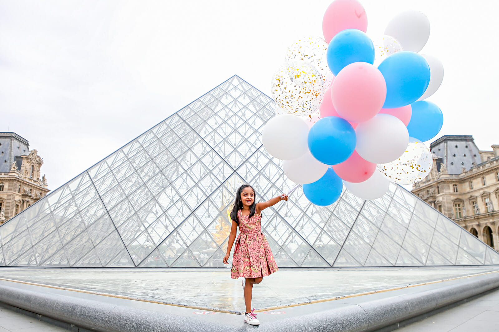 Solo portrait family photos at the Louvre Museum with pink, blue and white balloons