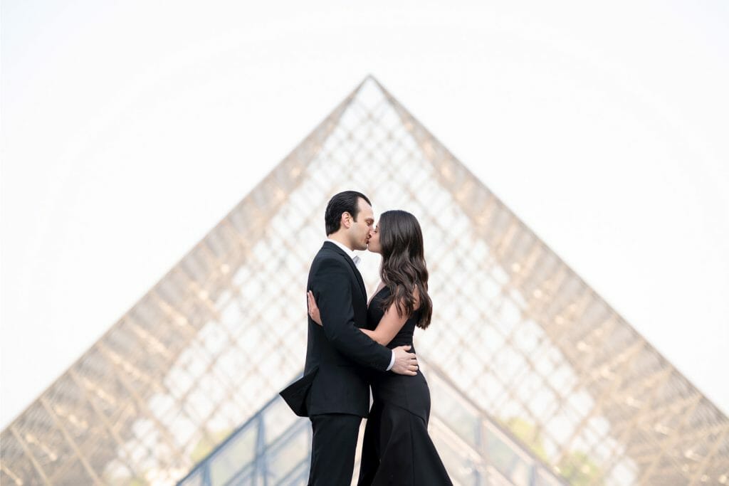 Hermosa sesión de fotos de pareja parisina en el Museo del Louvre frente a la pirámide.