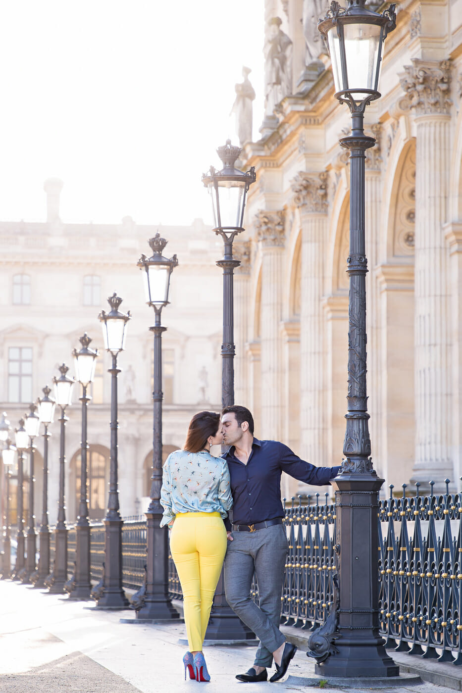Stylish couple kissing during their Paris engagement shoot near the Louvre Museum at sunrise