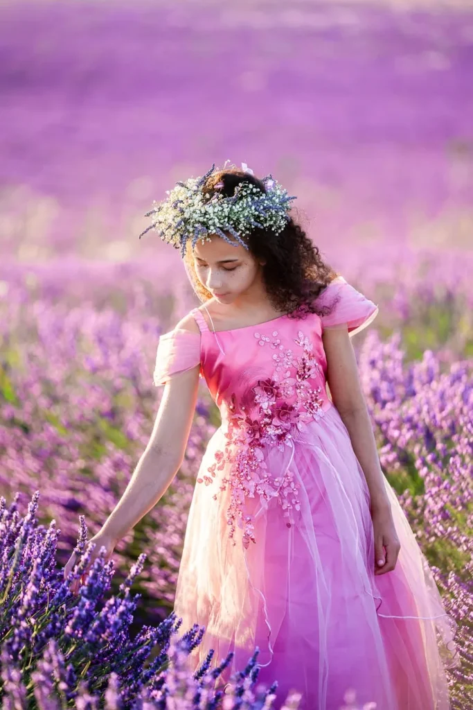Young girl in purple dress exploring blooming lavender fields in Provence during July family photoshootg