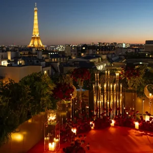 Секретный столик Peninsula Paris ночью: красная ковровая дорожка, кусты красных роз, свечи и мерцающая вдали Эйфелева башня.