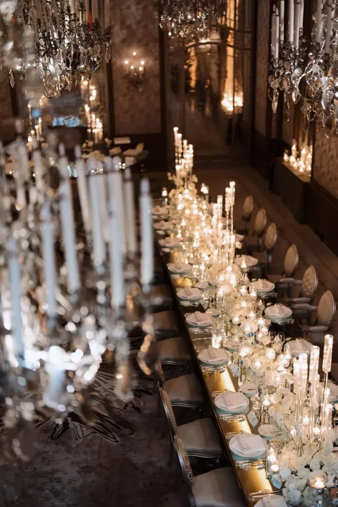 Lavish wedding reception planned by Chantelle Streete at Hotel Plaza Athénée, Paris, featuring mirrored glass tabletops, white rose centerpieces, and elegant chandeliers.