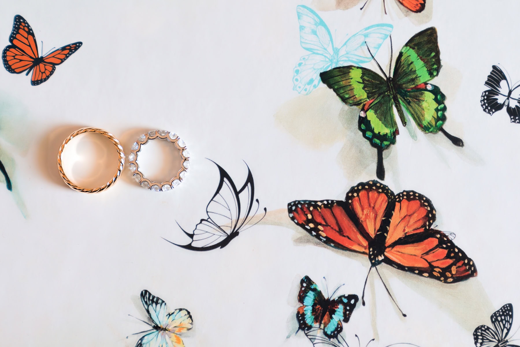 Luxury diamond wedding bands on an artistic French butterfly backdrop, representing Paris wedding planning, design, and style.