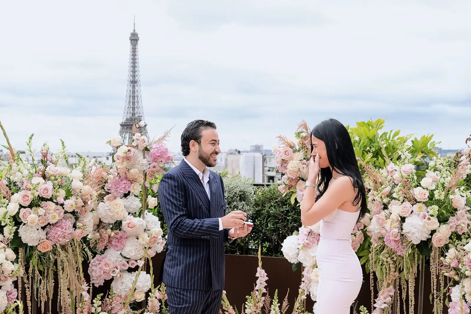 Невеста плакала от радости во время речи о предложении руки и сердца на фоне полной сервировки стола Peninsula Paris Secret Table и панорамного вида на Эйфелеву башню