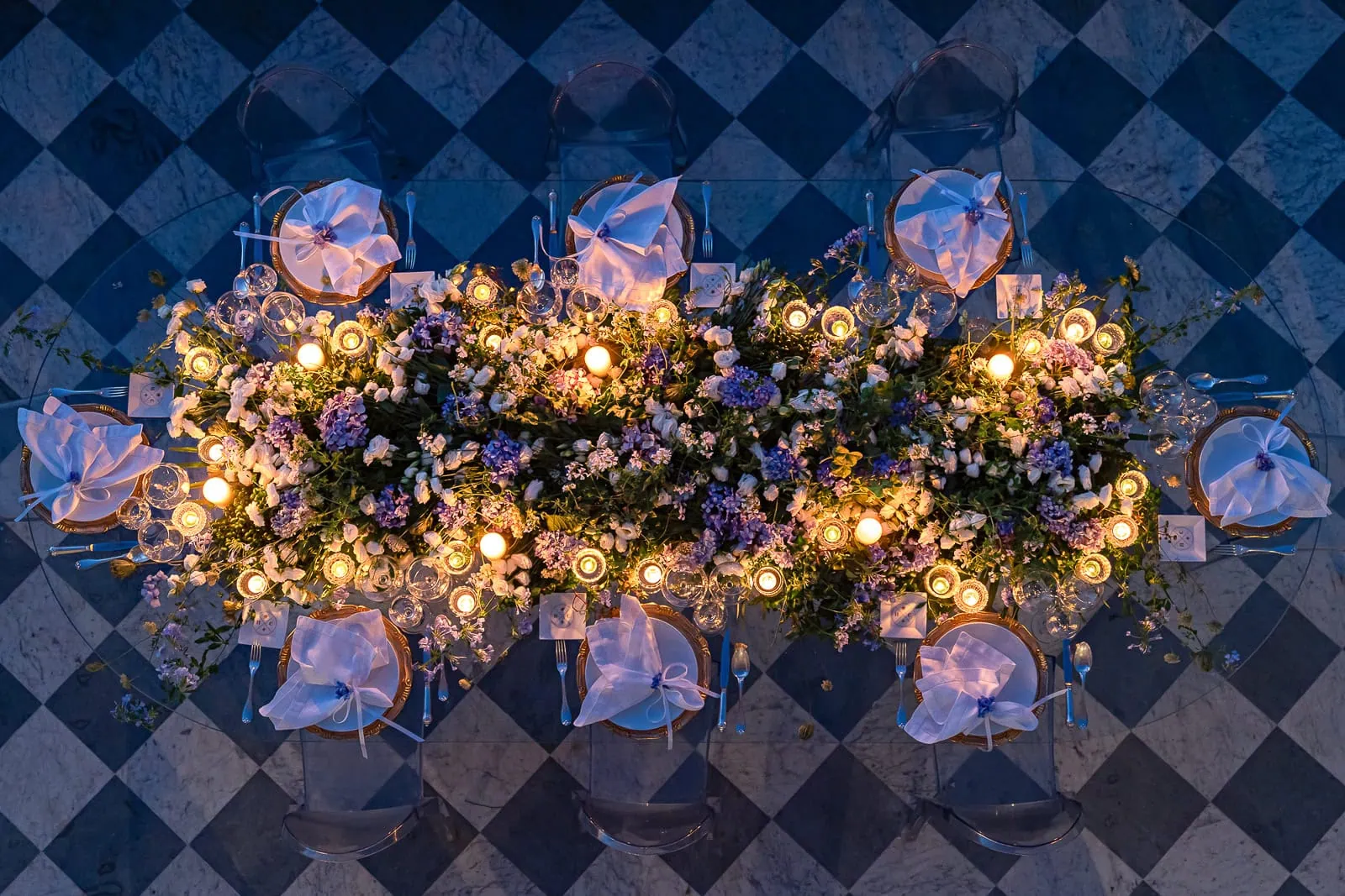 Intimate wedding reception tabletop at Villa Astor in southern Italy, featuring abundant pastel florals, soft candlelight, and eight elegant place settings.
