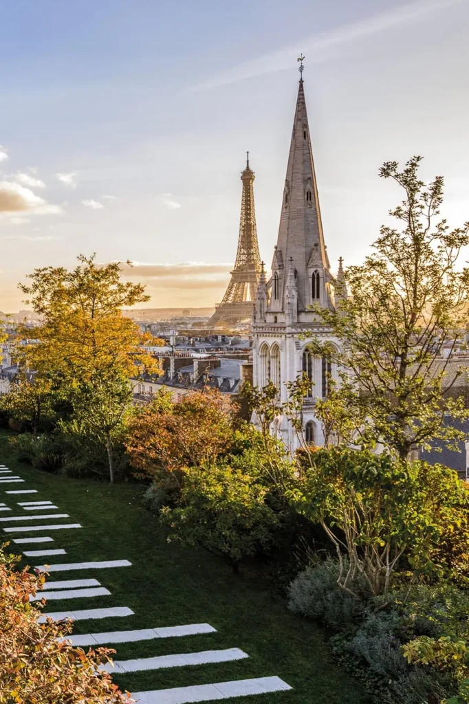 Terraza ajardinada del ático de Bulgari en París al atardecer: azotea privada con vistas a la Torre Eiffel, césped impecablemente cuidado, árboles otoñales y la aguja de Saint-Pierre-de-Chaillot.