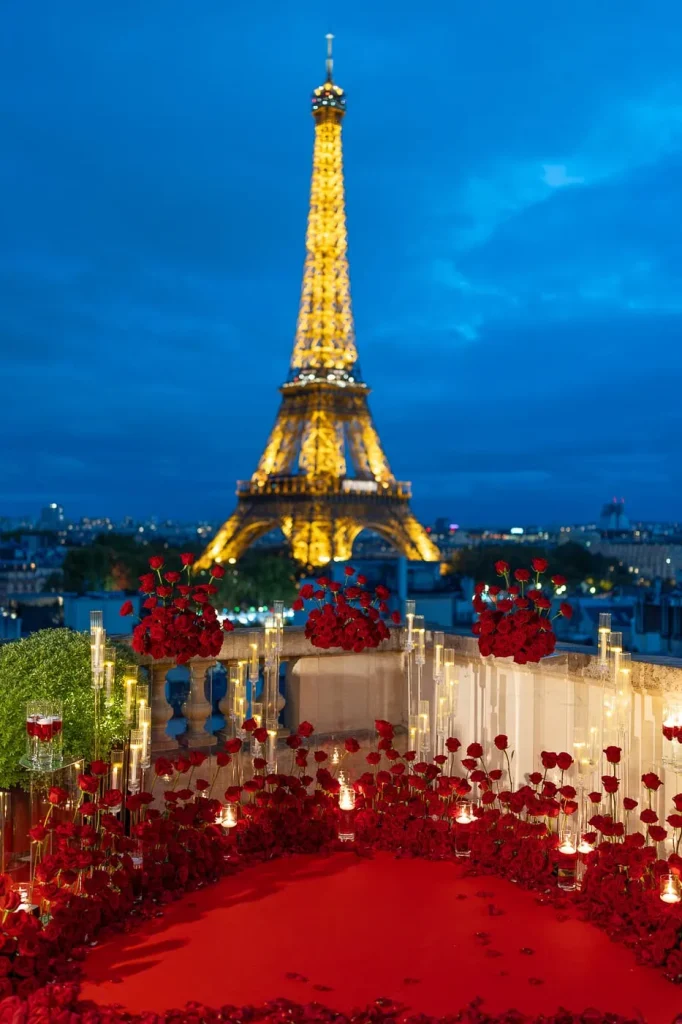Propuesta de boda en una suite privada con terraza en la azotea del Shangri-La Paris durante la hora azul: cientos de rosas rojas, columnas de velas, alfombra roja y la Torre Eiffel iluminada.